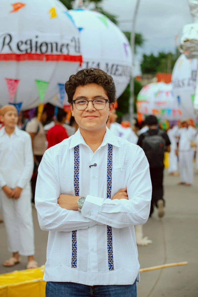 Young man in white embroidered shirt with arms crossed.